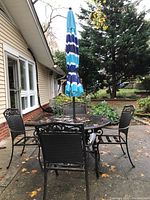 Full set on driveway showing round table with umbrella and four chairs in dark bronze finish