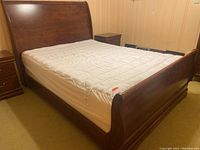 Full view of the bed showing wooden sleigh style frame and white mattress