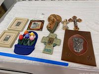 Full view of all religious and decorative items displayed on a bed, including framed prints, plaques, tulip holder, crucifix, carved bust, and Irish home blessing plaque.