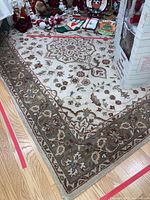 Wool rug on hardwood floor partially covered by Christmas décor, showing overall design and colors.
