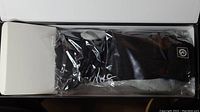 Photo showing a black heated sock sealed in plastic packaging housed in a white box.