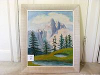 Full frontal view of framed oil painting showing winter mountain scenery with trees and sky.