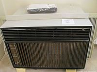 Front view of Kenmore window air conditioner showing grille and control panel with woodgrain detail and knobs.