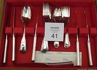 Full view of the silver plated flatware arranged inside the red velvet-lined wooden box showing all utensils in place.