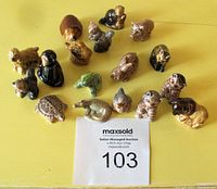 Seventeen small Red Rose Tea Wade porcelain animal figurines arranged on a yellow surface showing variety of animals and good condition.