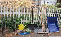 Wide view of lot including bundle buggy, watering can, various shovels, push broom, and assorted hand tools in box.