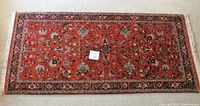 Top view of the Persian carpet runner laid flat on carpeted floor, displaying full length with red field and floral design.
