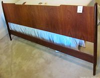 Full front view of the teak headboard showing its overall design and condition, with slight view of bed frame underneath.