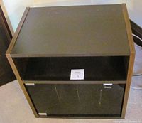 Full view of the cabinet showing the flat top shelf open space and lower section with closed glass door designed for vinyl record storage.