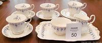 Full luncheon set arranged on table showing cups, saucers, serving platter, creamer, and sugar bowl. One tea cup has visible crack.