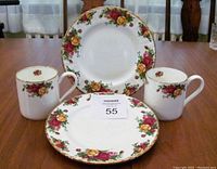 Four-piece set with two mugs and two plates arranged on table, showing floral pattern and gold trim.