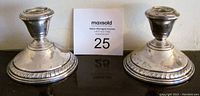 Pair of silver candlestick holders shown side by side with auction lot card