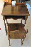 Photo of vintage wooden telephone table viewed from above showing turned legs and shelf below tabletop with raised edges.