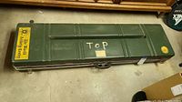 Closed green hard case labeled TOP, two latches, central handle