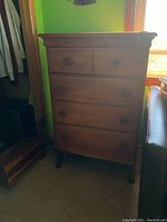 Tall solid wood dresser with four drawers, medium brown finish, two smaller top drawers and three larger bottom drawers, on curved legs, some surface scratches visible