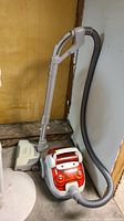 Full view of the Electrolux canister vacuum with hose and powerhead attached, showing dusty condition and basement environment