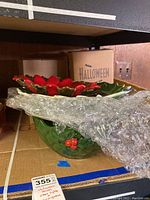 Photo showing the Halloween ceramic bowl with red floral accents partly wrapped in bubble wrap on a shelf
