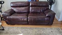 Full frontal view of the dark brown leather sofa showing two reclining ends, overall condition and upholstery detail.