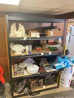 Frontal view of tall black metal shelving unit filled with various household and decorative items.