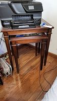 Photo of the pair of wooden nesting tables with storage under and glass inserts on the top, showing general shape, finish, and condition.