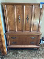 Front view of the wooden wardrobe cabinet showing the cabinet doors and drawers.