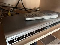 Front and top angled view of Toshiba DVD player showing remote control placed on top.
