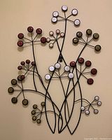 Full view of floral wall decor showing black metal stems with colored spherical petals in white, red, and greenish-yellow hues.