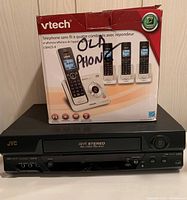 Photo showing boxed VTech cordless phones labeled 'OLD PHONE' on top of JVC VHS VCR unit