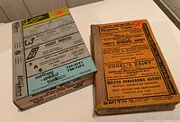 Two vintage city directories stacked, showing covers and advertising on Kingston Directory