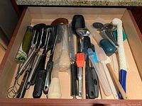 Drawer full of mixed kitchen utensils including basters, forks, spatulas, brushes, and cutters.