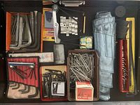 Photo showing various metal Allen keys, foldable screwdriver set, aluminum nails, nuts, and wrench roll-up pouch.