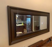 Mirror hung on wall horizontally, showing full frame and reflection of room.