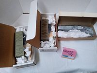 Lot including two green covered hopper cars and one gray locomotive packaged with foam packing peanuts inside original boxes.
