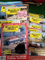 Photo showing multiple Railroad Model Craftsman magazine covers featuring trains and model projects, including SD60 drawings, steel mill locomotives and detailed modeling techniques.