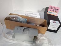 Image showing unassembled grey plastic model caboose body, parts in plastic bags, and instruction sheet inside cardboard packaging.