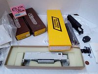 Overview of the lot showing Westerfield train kits in brown boxes, a yellow Rail Power Products box, unassembled white plastic car body, black chassis and detail parts in plastic bags.