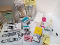 Photo showing various HO scale kits and parts including boxed 15 Ton Truck Crane, USRA Steel Side Rebuild kit, operating signal, and many smaller parts in sealed bags and boxes.
