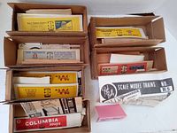 Multiple cardboard boxes each containing vintage Red Ball model train kits with labeled boxes and assembly sheets visible.