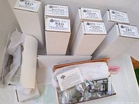 Overview of nine tall white kit boxes and two open boxes showing bagged parts and instructions