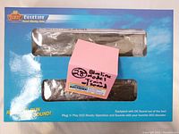 Photo of Broadway Limited BlueLine HO scale model train in blue packaging with window showing the locomotive and tender, and a pink post-it note annotation.