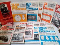 13 volumes of Train Shed Cyclopedia magazines with distinct colored covers and train illustrations, showing vintage style and indexing.