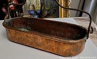 Side view of the elongated copper bucket showing the hammered texture and patina.