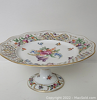 Side view of the compote showing the floral painted decoration, reticulated rim and gold trim.