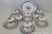 Full view of front set including cups, saucers, plates, creamer, and sugar bowl showing floral pattern and gold trim