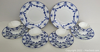 Image of the full set showing cups, saucers, and plates with blue floral decoration on white porcelain.