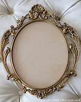 Full view of the oval-shaped gilt metal frame showing its detailed Rococo style edge and shell motifs.