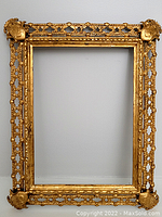 Full frontal view of the rectangular gilt metal frame showing ornate corner decorations and openwork lattice pattern on the border.