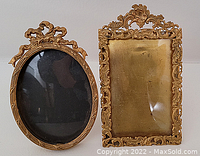 Front view of two ornate gold-toned easel photo frames, one oval and one rectangular