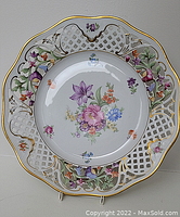 Front view of large porcelain plate with reticulated rim and hand-painted floral design
