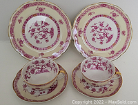Two sets of Haviland Limoges porcelain trios, each with a teacup, saucer, and plate featuring pink floral patterns and gold accents.